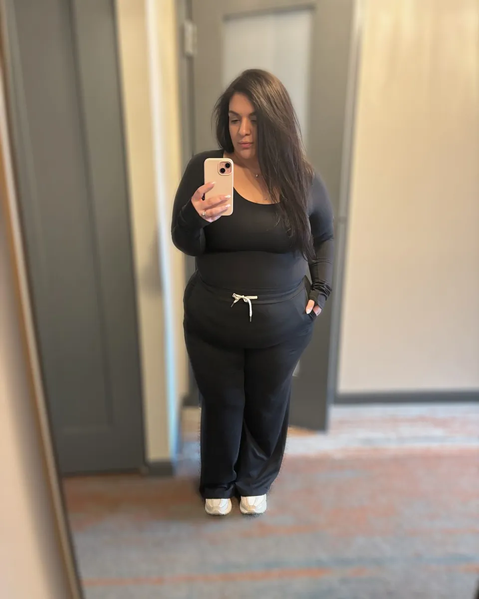 Catlina en photo miroir dans un couloir, ensemble noir et baskets blanches