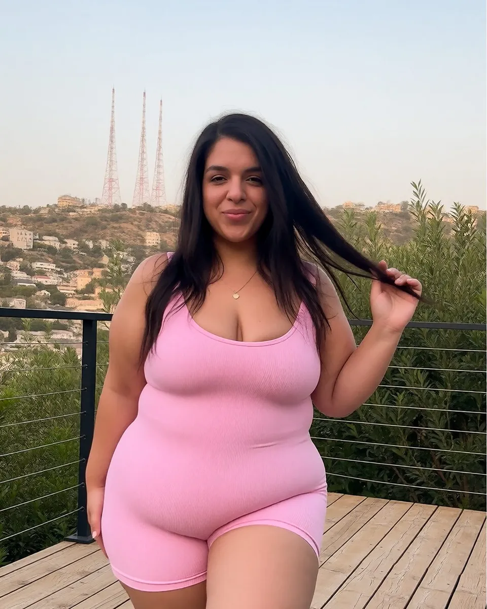 Catlina en combinaison de sport rose sur un tapis de yoga, terrasse en bois