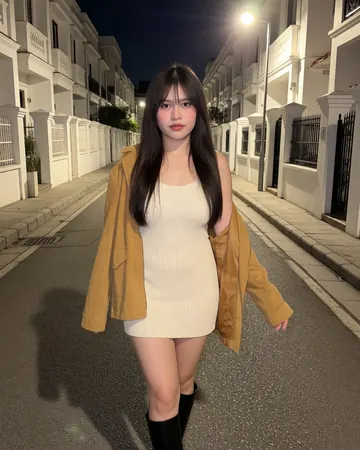 Elisa on a street in the evening, mustard cardigan and cream dress
