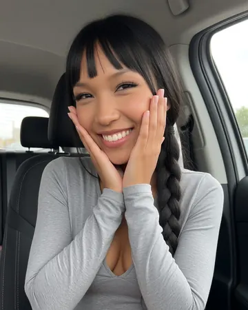 Jade taking a selfie in a car, fringe and long black braid, big smile