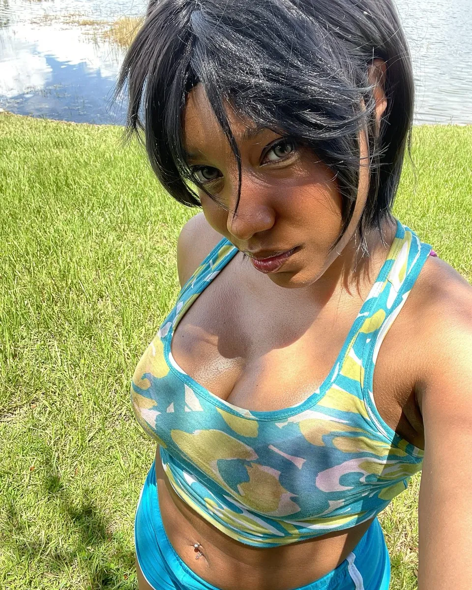 Maya en perruque courte noire dans l'herbe, brassière colorée