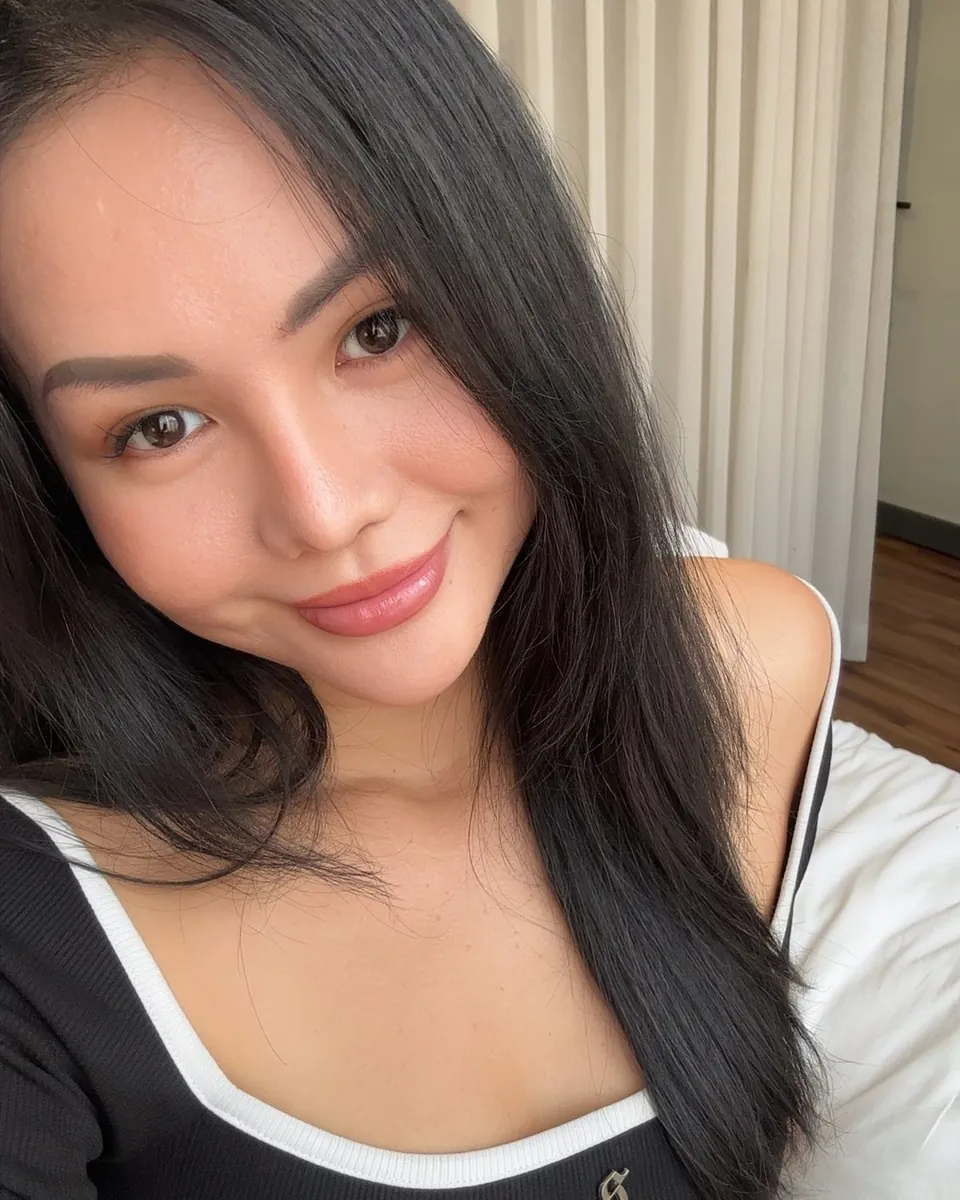Mia im Selfie, lange schwarze Haare, sanftes Lächeln, schwarzes Top mit weißem Rand