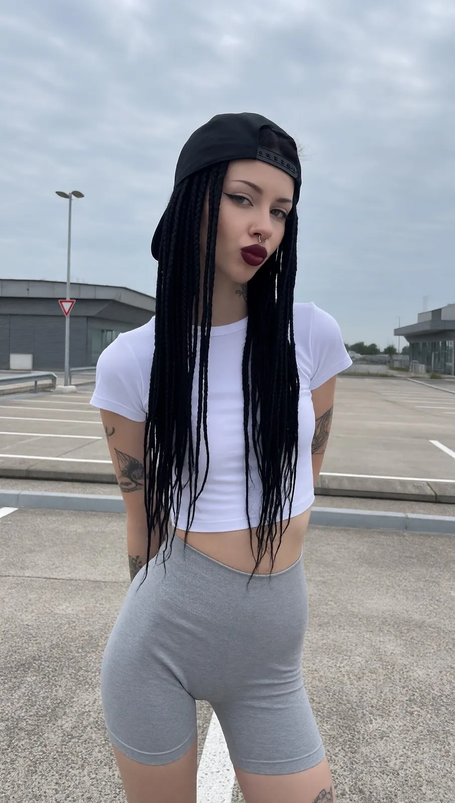 Vera sur un parking, casquette noire et t-shirt blanc
